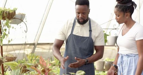 Specialist Explains Plant Care to Engaged Client in Nursery
