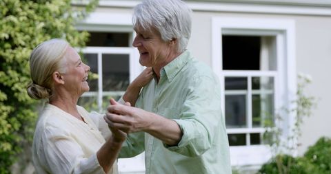 Senior Couple Joyfully Dancing in Garden Embracing Love