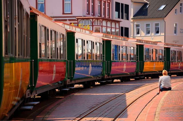 Person Sitting Alone Near Colorful Train in European City - Download Free Stock Photos Pikwizard.com