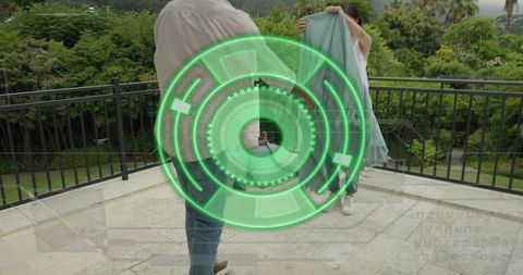 Couple on terrace holding light green garment with futuristic neon hud overlay