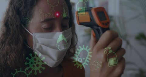 Woman with face mask and infrared thermometer amidst covid-19 icons