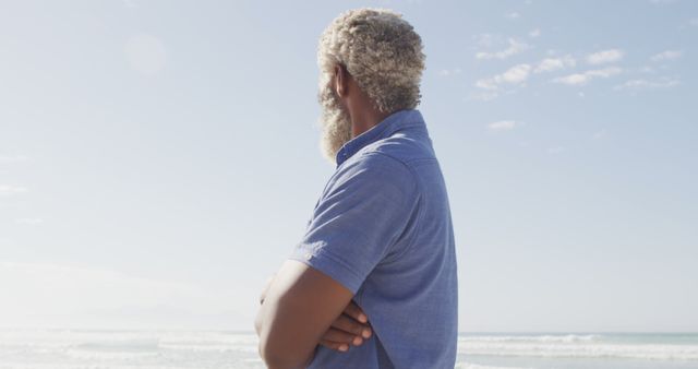 Senior african american man looking away on sunny beach. healthy and active time beach holiday.