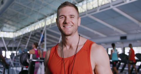 Cheerful fitness coach in gym with exercising people