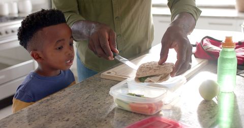 Grandfather preparing sandwiches with grandson in kitchen