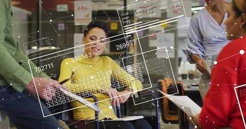 Team collaborating at office with augmented reality data overlays and woman taking notes