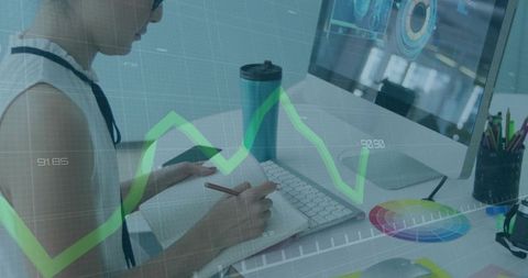 Woman writing notes at desk with computer analytics overlay, color wheel and keyboard