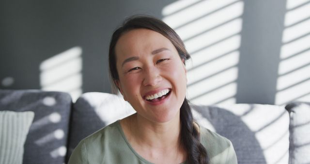 Smiling Woman Sitting on Couch with Light Through Blinds - Download Free Stock Images Pikwizard.com