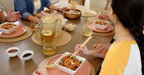 Diverse family sharing meal with noodle salad at home table