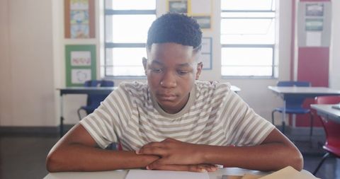 Focused Teenage Student at Classroom Desk Examining Notes