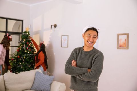 Diverse Friends Trimming Christmas Tree in Modern Living Room