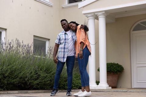 African american couple leaning on porch columns with lavender and casual style