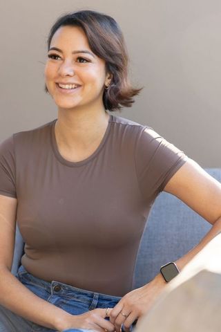 Smiling african american woman wearing smartwatch and rings, casual jeans and brown tee