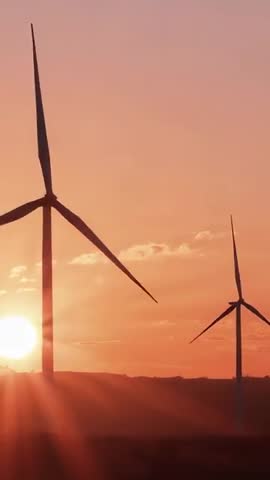 Golden Hour Wind Turbines Spinning on Hills Vertical Footage with Sun Flare and Silhouettes