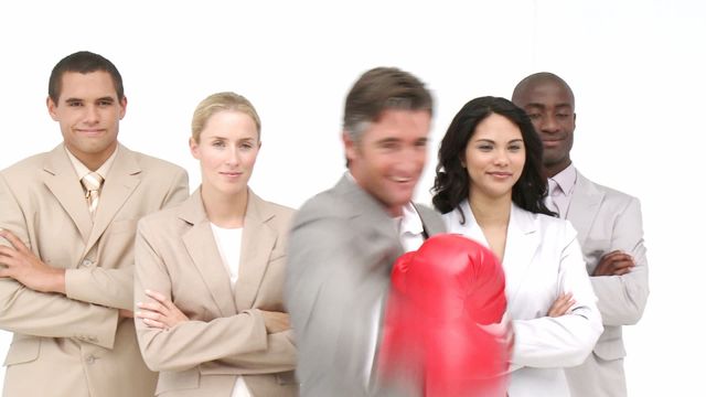 Businessman wearing red boxing gloves posing confidently in front of professional team, symbolizing motivation, assertiveness, and strong leadership. Team members stand with arms crossed, expressing support and determination. Suitable for concepts like inspiration in business environments, teamwork dynamics, or competitive work strategies.