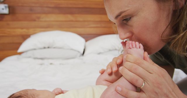 Image of happy caucasian mother kissing feet of newborn baby. motherhood, parental love and taking care of newborn baby concept digitally generated image.