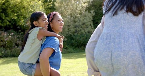 Mother and Daughter Enjoying Playful Piggyback Ride Outdoors