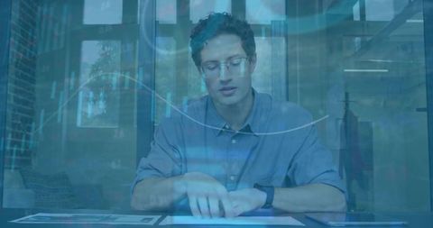 Designer reviewing prints with holographic data overlay and smartwatch in modern office
