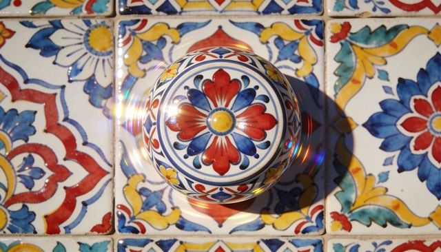 Hand-painted talavera ceramic knob on colorful glazed tiles with sunlit rainbow flare