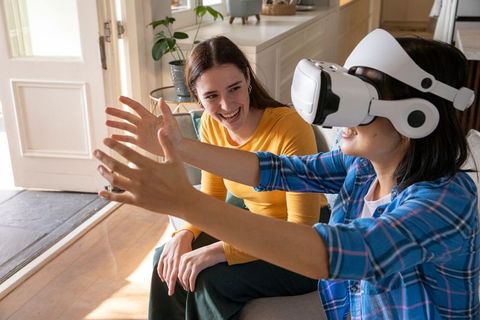 Smiling Friends Enjoying Virtual Reality Indoors on a Comfortable Sofa