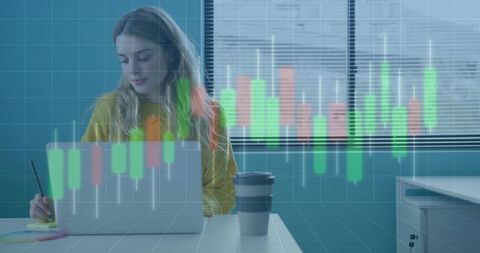 Young woman working on laptop taking notes with candlestick trading chart overlay