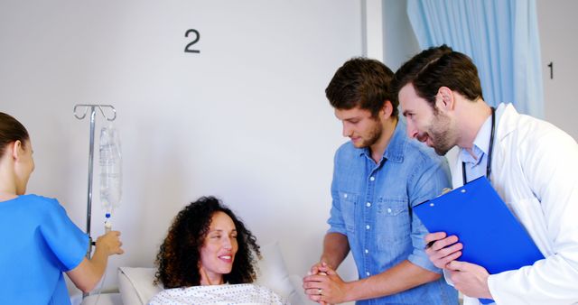 Medical team consisting of doctor and nurse assisting female patient in hospital room. Male family member is holding patient’s hand, showing support and care. Useful for topics related to healthcare, recovery, patient care, medical support, and hospital environment.