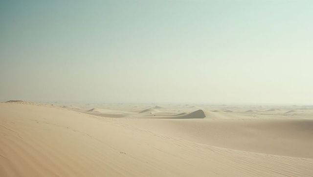 Vast Desert Landscape with Rippled Sand Dunes under Clear Sky