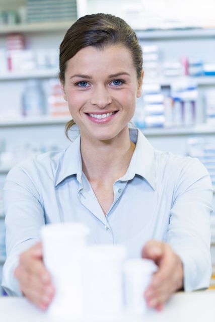 Smiling pharmacist holding medicine container in pharmacy - Download Free Stock Photos Pikwizard.com