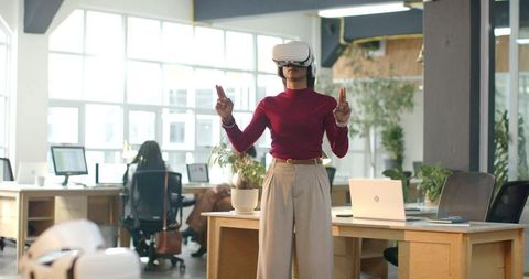 African American woman using VR headset in modern open office for team collaboration
