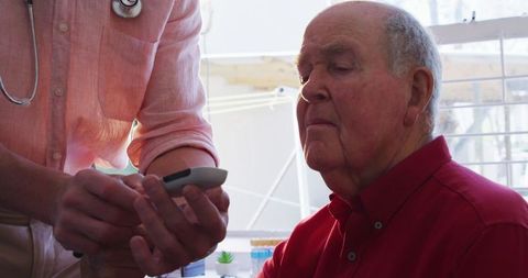 Doctor Checking Senior Patient's Blood Sugar in Retirement Home Clinic