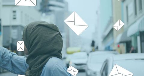 Woman in city street surrounded by digital mail icons