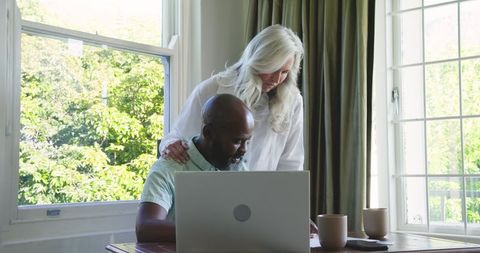 Mature Couple Collaborating with Laptop in Bright Cozy Room