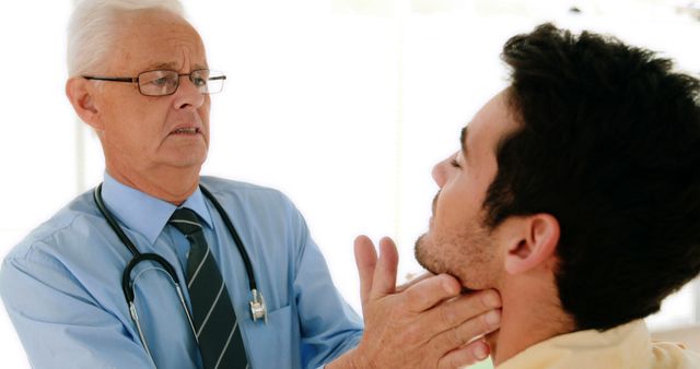 Doctor conducting throat examination on a male patient in a clinical setting. Useful for illustrating medical consultations, healthcare services, or doctor-patient interactions. Ideal for healthcare marketing materials, medical education articles, and wellness guides.