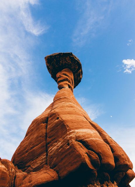 Tall rock formation captured against bright blue sky, showcasing unique geological features and erosion patterns commonly found in desert environments. Ideal for use in travel blogs, nature magazines, educational materials on geology, or advertisements promoting outdoor adventures and tourism.