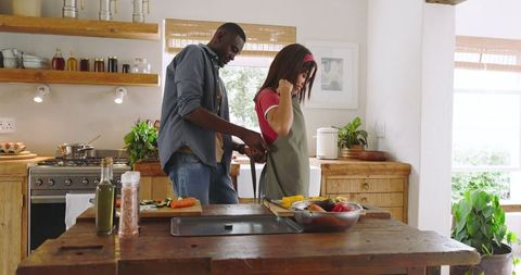 Couple cooking together chopping vegetables in cozy kitchen