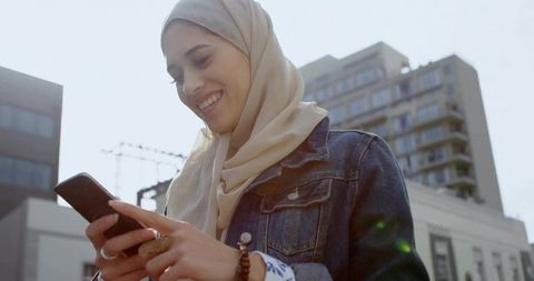 Smiling Woman in Hijab Using Smartphone in City plaza