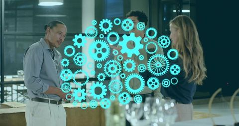 Discussing digital workflow with teal gear overlay in modern office collaboration lounge