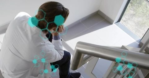 Researcher resting on staircase contemplating results with teal molecular overlays alone