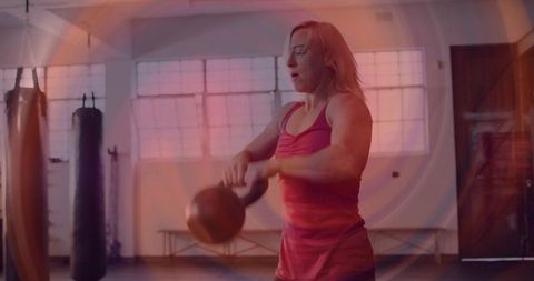 Woman swinging kettlebell in gym for explosive strength and conditioning workout