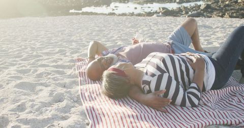 Interracial Senior Couple Relaxing on Sunny Beach Blanket