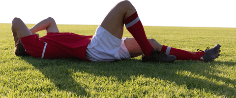Exhausted rugby player lying on grass under clear sky