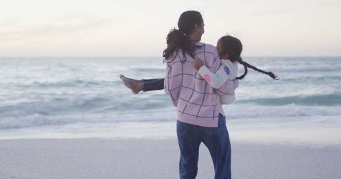 Mother Carrying Daughter on Beach During Sunset