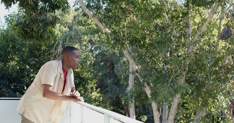 Man Relaxes on Balcony Surrounded by Lush Green Trees