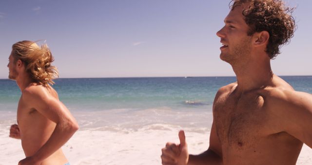 Two young athletic men jogging along sunny beach - Download Free Stock Images Pikwizard.com