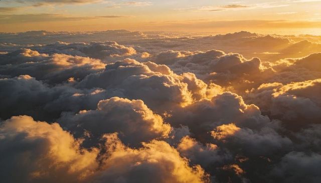 Glowing rim-lit cumulus cloudscape floating above horizon at sunrise, golden backlight