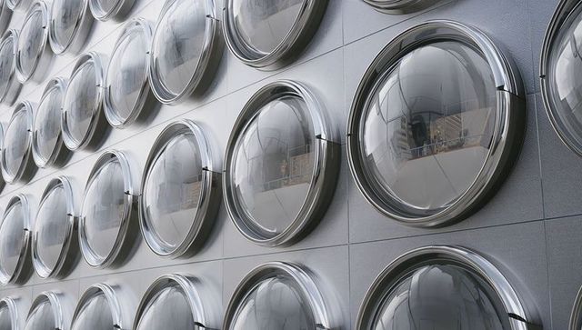 Hemispherical glass portholes repeating on metallic building facade with chrome bezels