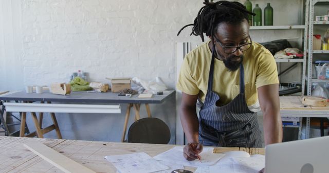 African American man reviews plans in a workshop. His focus on the project reflects dedication and craftsmanship at home.