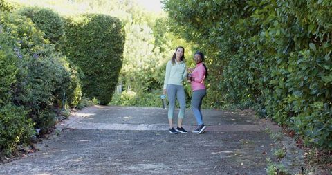 Diverse Female Friends Enjoying Fitness Walk in Lush Greenery