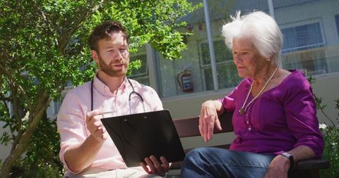 Doctor Consulting Senior Woman Outdoors in Sunny Day