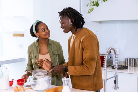African american couple baking together on bright modern kitchen island smiling