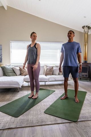 Couple practicing morning home workout on yoga mats tracking heart rate with smartwatch
